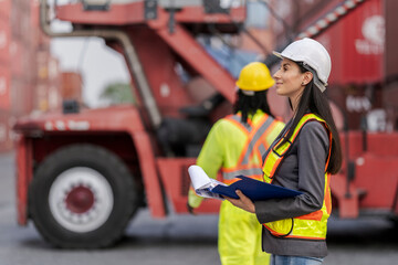 Team logistics workers in high visibility safety gear and hard hats discuss operations at a busy...