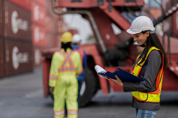 Team logistics workers in high visibility safety gear and hard hats discuss operations at a busy...