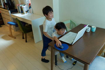 Obraz premium 自宅の部屋でパソコンを操作する2人の男の子
