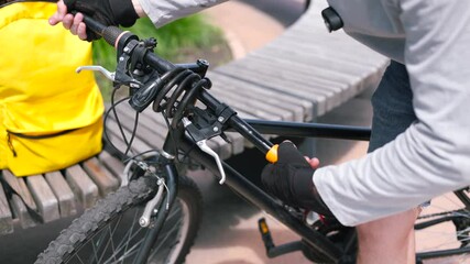 Hands of a bicycle mechanic installing new handlebar grips, replacing worn-out ones. Bike repair, diagnostics, and adjustment of cycling components. Manual maintenance of eco transport