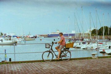 Fototapeta premium an old person riding a bike along the pier on the Belgian coast, in warm tones shot on film