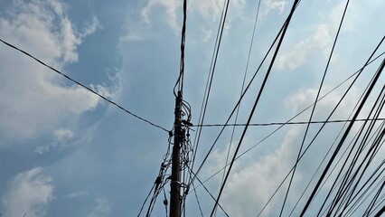 Electric cables lying across the top, seen against a background of blue sky and clouds. Background...