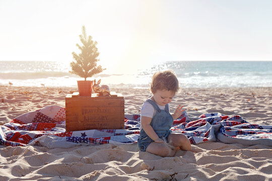Small Girl Sitting In a Christmas Themed Setting At The Beach At Sunset