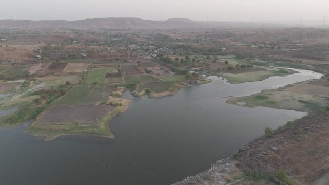 Raw footage of wind farm near beautiful lake and mountains. 3840 x 2160 px and 59.94 fps raw D log M aerial footage 26 second length.