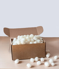 Biodegradable cornstarch packing peanuts filling an open cardboard box, safe product shipment while being environmentally friendly, practical and eco-conscious solution for modern packaging needs