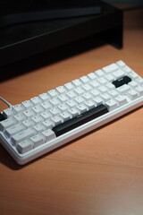A wired 65% mechanical keyboard with a monochrome (black and white) theme on a wooden table.
