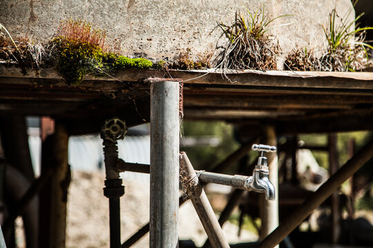 Outside tap on a moss covered concrete tank stand