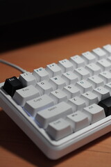 A wired 65% mechanical keyboard with a monochrome (black and white) theme on a wooden table.
