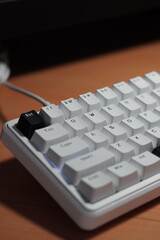 A wired 65% mechanical keyboard with a monochrome (black and white) theme on a wooden table.