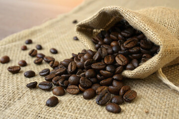 Fototapeta premium Rustic close-up of fragrant coffee beans overflowing from a textured burlap pouch, ready for brewing.
