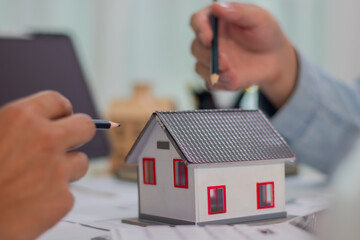 Architect and businessman discussing interior mansion plans using pencils and models at desk, including real estate purchase planning with leaders, marketing and engineering insights.