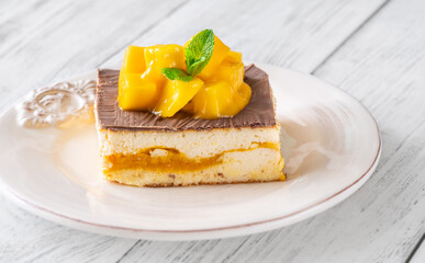 Chocolate-Glazed Mango Cheesecake Square Topped With Mango Cubes and Mint Leaf