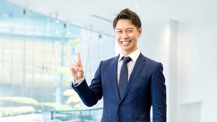 人差し指を立てて案内する男性ビジネスマン