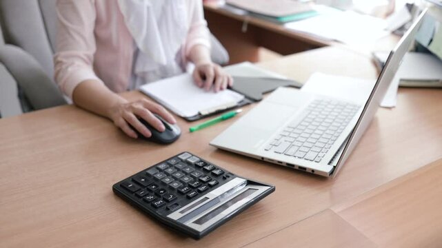 Asian woman working at the office use cell phone and calculator and laptop