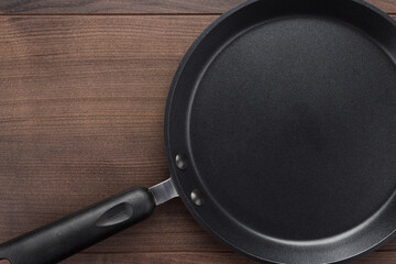 Photo of frying pan on wooden background with copy space.