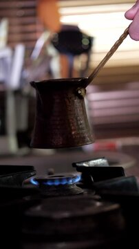 An aromatic and traditional mood is captured as dark, rich Turkish coffee simmers and brews in a classic copper cezve pot on a gas stove, with subtle steam rising