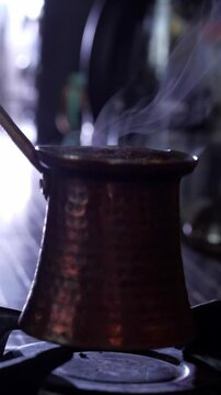 An aromatic and traditional mood is captured as dark, rich Turkish coffee simmers and brews in a classic copper cezve pot on a gas stove, with subtle steam rising
