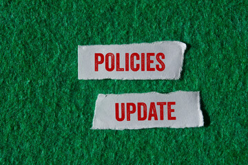 Policies update message written on ripped torn paper pieces on green background. Conceptual...