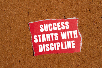 Success starts with discipline message written on ripped torn red paper piece on brown background....