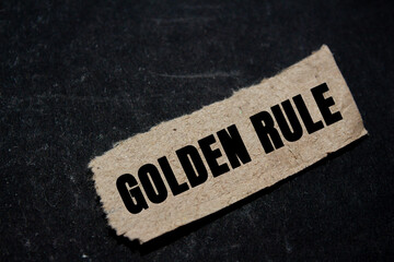 Golden rule message written on ripped torn paper piece on black background. Conceptual golden rule...