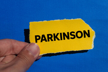 Parkinson message written on ripped torn yellow paper piece on blue background. Conceptual...