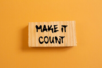Make it count message written on wood piece on orange background. Conceptual make it count symbol. Copy space.
