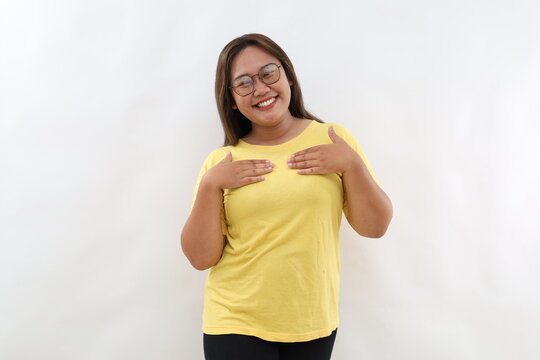 Photo of lovely sincere Asian woman with dark hair tilts head feels happy feels glad wears casual t-shirt isolated over white background. Happy asian female model glad to get compliment