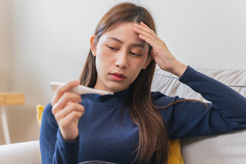 Sick day at home. Asian woman check temperature at home.