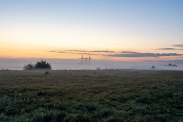 In a rural area, the morning smog enveloped the masts of high-voltage power lines. Early in the...