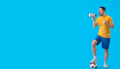 Male coach with soccer ball and megaphone on blue background with space for text