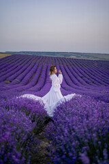 A woman in a white dress is standing in a field of purple flowers
