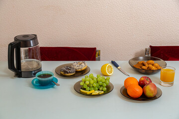 The dining table on it has fruits, juice, cakes, tea