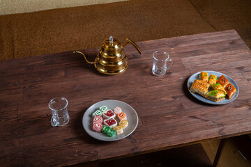 Oriental sweets baklava and lukum on a dark wooden table next to a Turkish teapot and cups