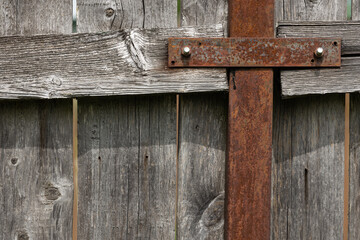 Close-up of a weathered wooden fence with a rusty metal crossbar. The texture shows aged wood and metal, creating an abstract background.