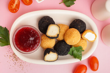 Plate with different delicious fried mozzarella balls, tomatoes and sweet sauce on pink background