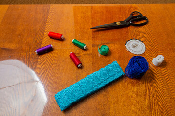 Sewing and knitting threads, knitting needles, measuring tape and scissors on the table in the room