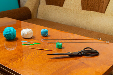 There is a horizontal photo of threads, knitting needles, measuring tape