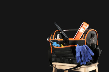 Stepladder with electrician tool bag on black background, closeup