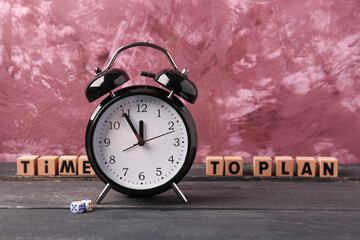 Cubes with text TIME TO PLAN and alarm clock on wooden table against pink background. Time...