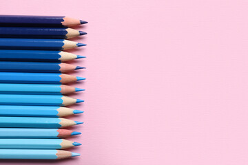 Blue pencils on pink background, closeup