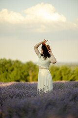 A young brunette walks in wheat fields at sunset in summer. Growing organic wheat and barley.