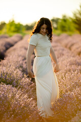 A young brunette walks in wheat fields at sunset in summer. Growing organic wheat and barley.