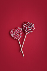 Heart lollipops candy on a stick on red background