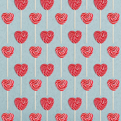 Pattern from heart lollipops candy on a stick on blue background