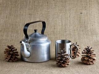 Aluminum army teapot from the Second World War. Stylized still life with a cup and pine cones....