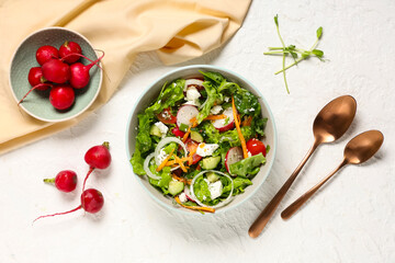 Bowl of fresh vegetable salad with radish and feta cheese on white background
