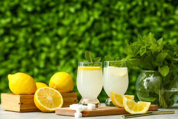 Glasses of fresh lemonade with mint and sugar on grey table outdoors
