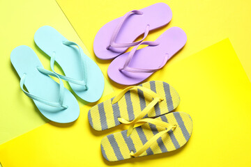 Different stylish flip-flops on yellow background