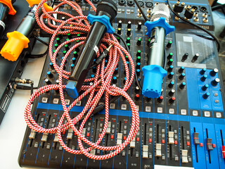 audio mixer console, along with messy microphones and cables on top of it.