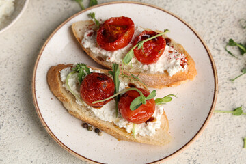 Plate of tasty tomato bruschetta with ricotta and micro green on white background